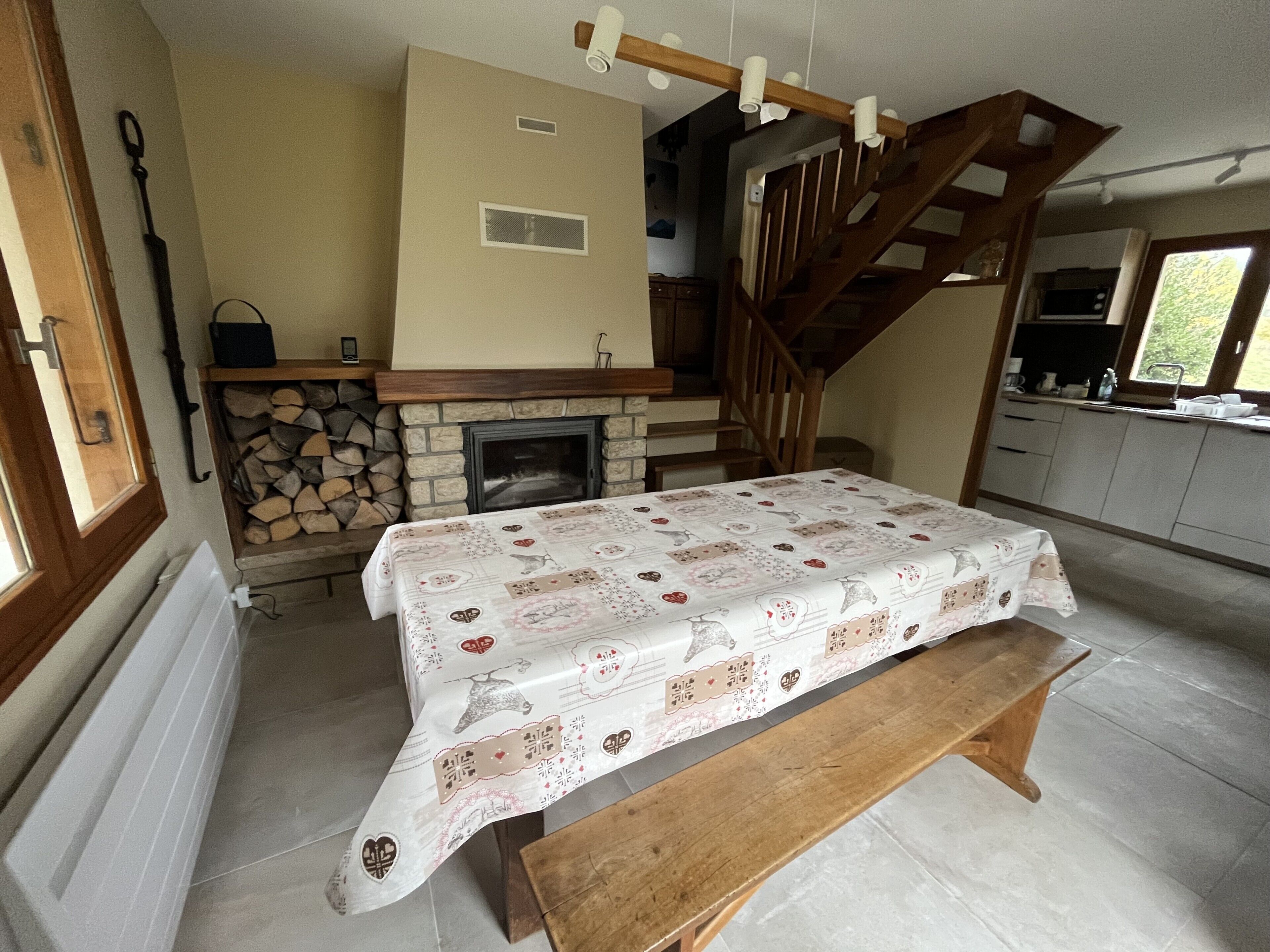 Una cocina acogedora con chimenea, escalera de madera y una mesa de comedor para dos.