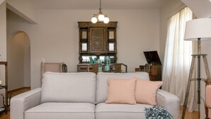 A living room with a sofa, a wooden coffee table, and a chandelier. - Spacious house with terrace combining tradition and modernity near sandy beach (Tinos)