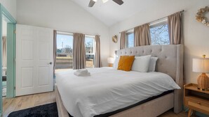 Une chambre avec un grand lit, un ventilateur de plafond et une vue sur l’extérieur.