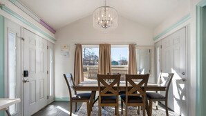Un espace repas comprenant une table et des chaises, un lustre et une vue sur l’extérieur.