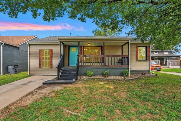 A single-story house with a front porch, a blue door, and a small front yard.