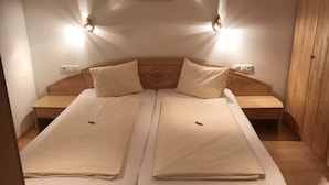 Una cama doble con dos almohadas, cabecero de madera, mesitas de noche e iluminación en la pared.
