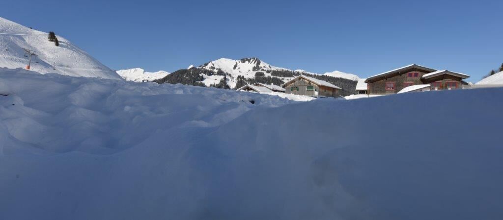 Ein schneebedeckter Berg mit einer Seilbahn und Gebäuden im Hintergrund.