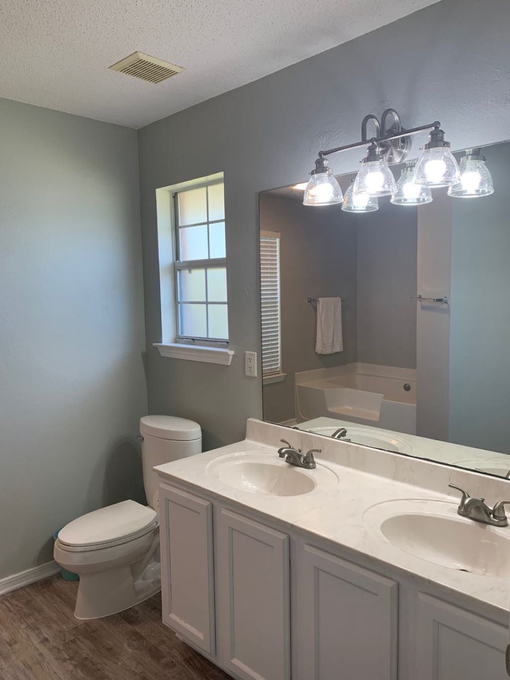 A bathroom with two sinks, a toilet, a window, and a mirror.