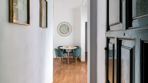 Een gang die uitkomt in een eetgedeelte met een ronde tafel en stoelen, foto's in de wanden en een houten vloer.
