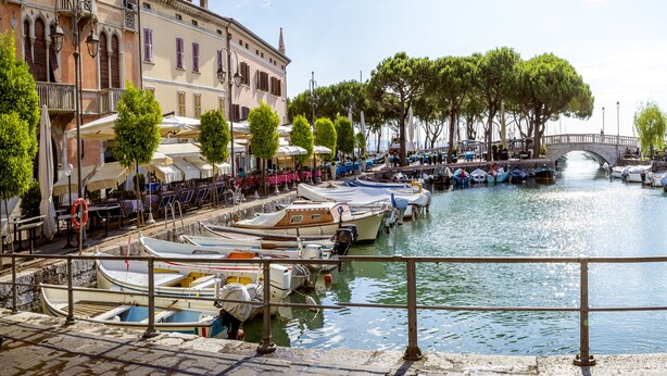 A canal with boats docked, a bridge, and buildings with outdoor seating. - Villa Mimosa - Apt 2 (Desenzano del Garda)