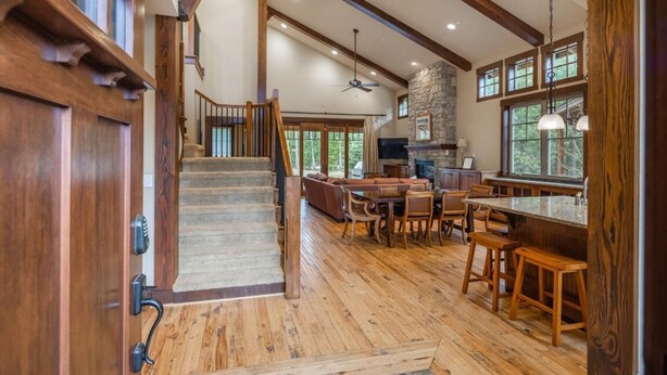 Un intérieur spacieux agrémenté d’un escalier en bois, d’une cheminée en pierre et d’un coin repas avec des meubles en bois.