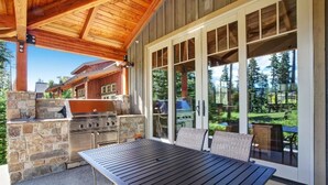 Une terrasse extérieure avec une cheminée en pierre, un barbecue et une table avec des chaises.
