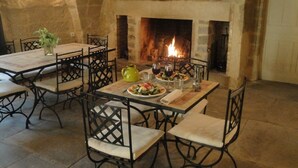 A dining area with a stone fireplace, wooden tables, and metal chairs.