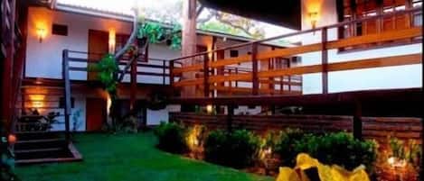 A building with a wooden balcony, a staircase, and a well-maintained lawn.