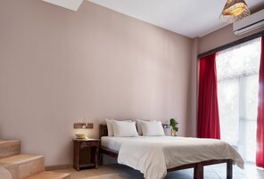 Un dormitorio con cama, mesita de noche, lámpara y ventana con cortinas.
