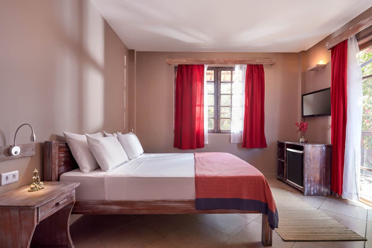 Ein Schlafzimmer mit einem Bett, einem Schreibtisch, einem Fernseher und einem Fenster mit Vorhängen.