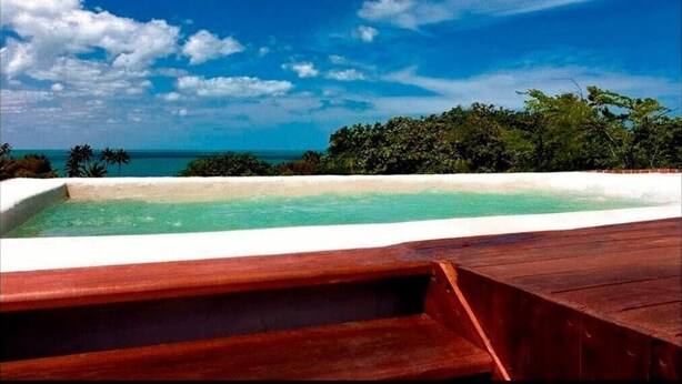 A wooden deck with a pool and a view of the ocean and trees. - All Blue (Jijoca de Jericoacoara)