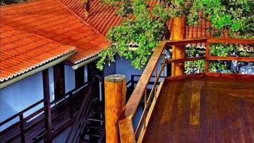 Um deck de madeira com uma escadaria que leva a um edifício com telhado de telhas vermelhas.