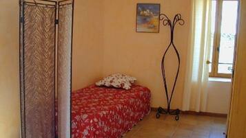 A room with a bed, a window, a door, and a painting on the wall.