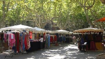 An outdoor market with various stalls selling clothes under white and orange canopies.