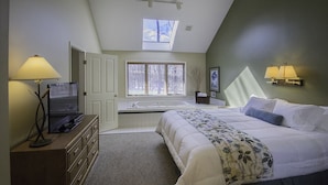 A bedroom with a bed, a desk, a chair, a window, and a skylight.