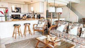 Een moderne keuken met witte kastjes, een centraal eiland en barstoelen.
