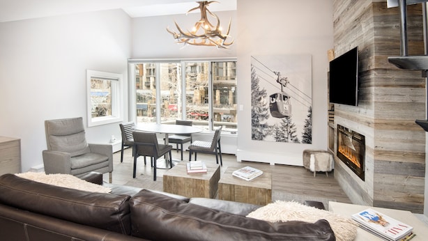 Een moderne woonkamer met een open haard, een eethoek en grote ramen met uitzicht op de stad.