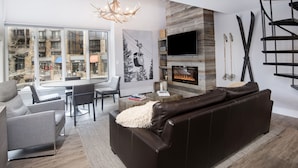 Een moderne woonkamer met een open haard, een groot raam en een trap.