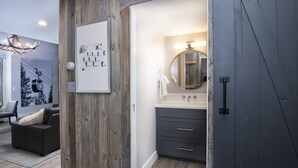 Een moderne badkamer met een houten accentmuur, een grote spiegel en een grijs badkamermeubel.