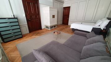 A bedroom with a large grey sofa, a small round table, and a white wardrobe.