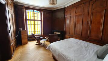 A bedroom with a large bed, wooden wardrobe, and a window with yellow blinds.