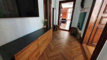 Een gang met een houten vloer, een zwart aanrecht en een potplant.