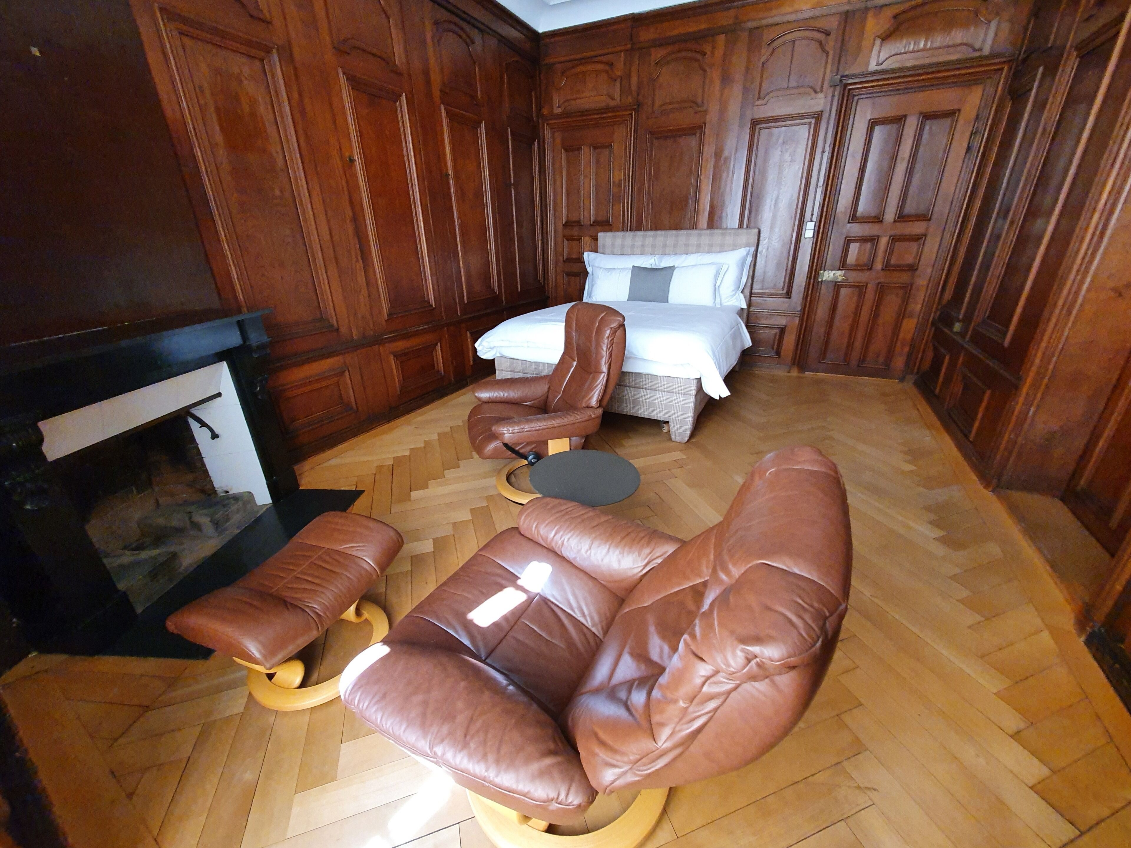 Ein Zimmer mit Kamin, einem Bett und Ledersofas.