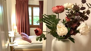 A hotel room with a wooden desk, a vase of flowers, and a sign reading "Gartenbuch".