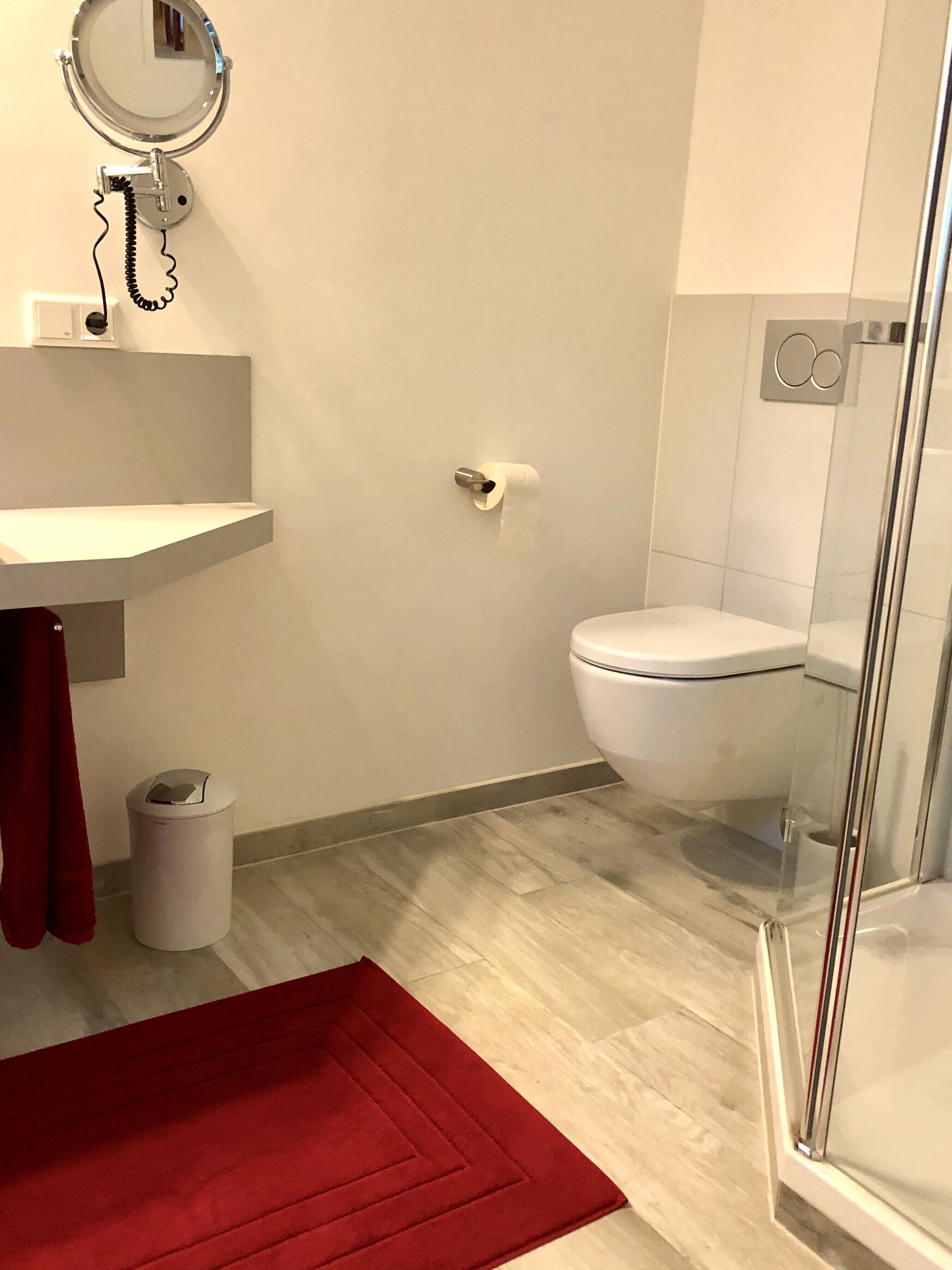 A bathroom with a toilet, sink, and mirror.