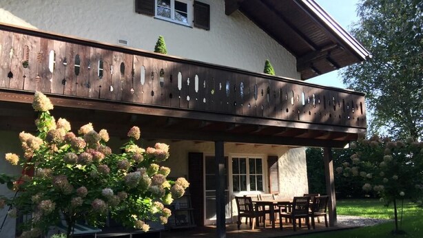 A two-story house with a covered patio area featuring a dining table and chairs.