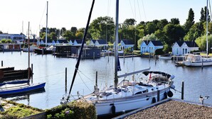 Ein Yachthafen mit vertäuten Booten, eine Reihe blauer Häuser und ein klarer Himmel.