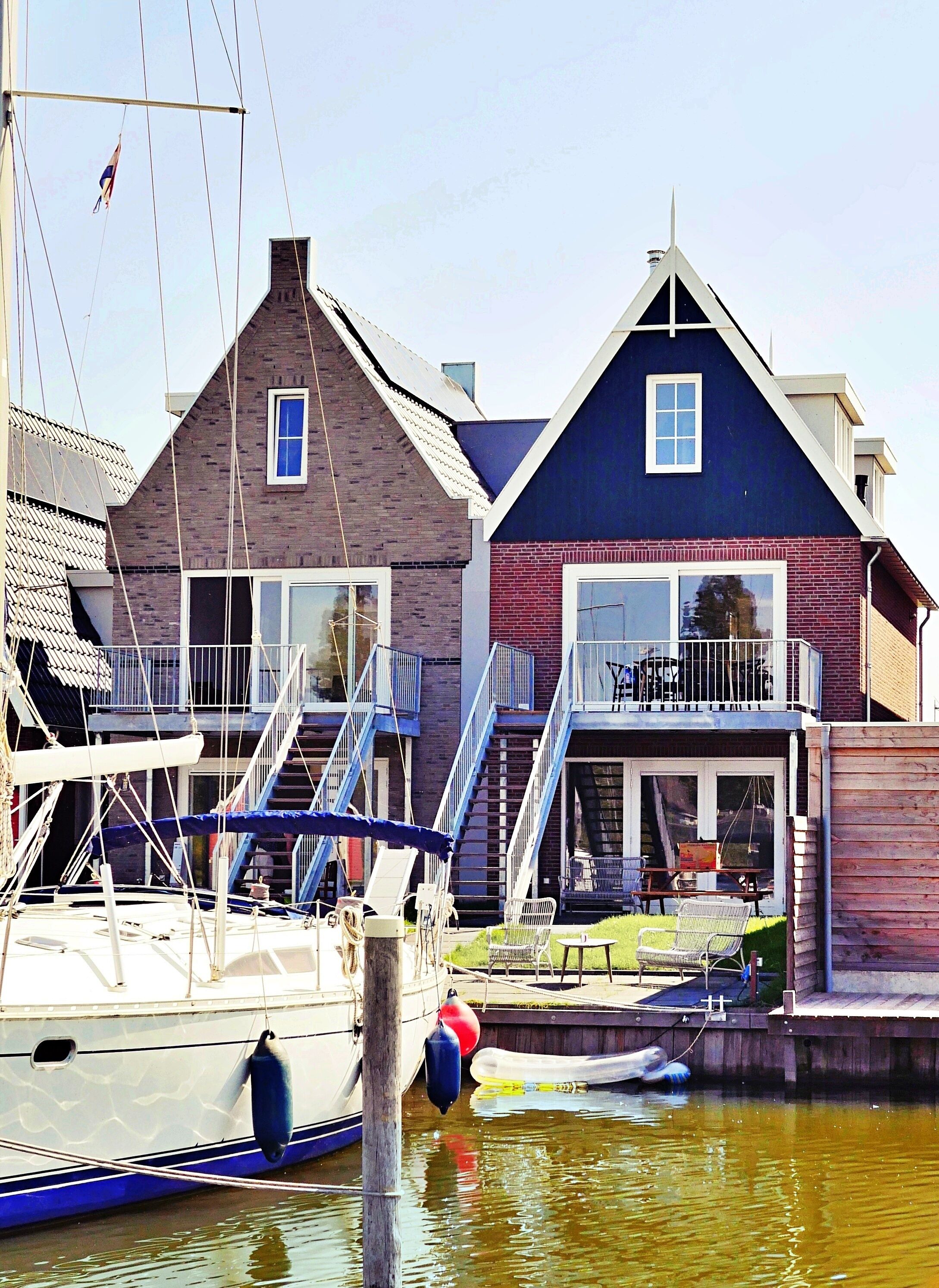 A waterfront property with a dock, a boat, and a building with a balcony.