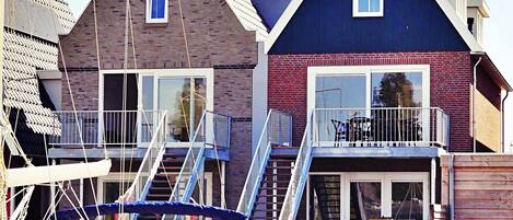 A waterfront property with a dock, a boat, and a building with a balcony.