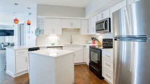 A modern kitchen with white cabinetry, stainless steel appliances, and a central island. - Summer House 201B | Beach views and deck access from every room! (Orange Beach)