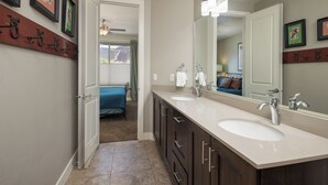 Une salle de bain moderne avec deux lavabos, un grand miroir et un ventilateur de plafond.