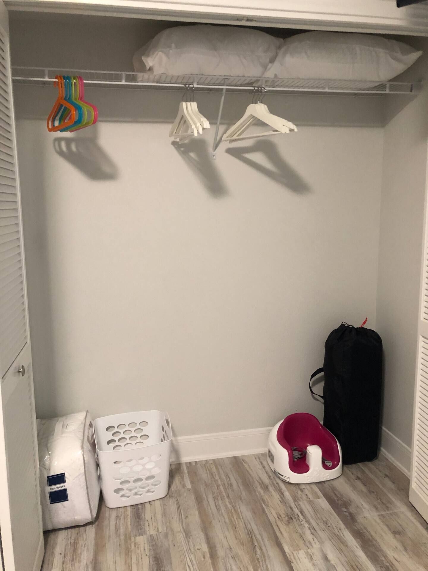 Een kast met kleding, een opbergdoos, een wasmand en een rood po.