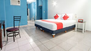 Un dormitorio con una cama, una silla, una mesita de noche y una puerta que da a otra habitación.