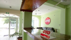 Una mesa de recepción con un letrero que dice "OYO" y una planta en maceta.