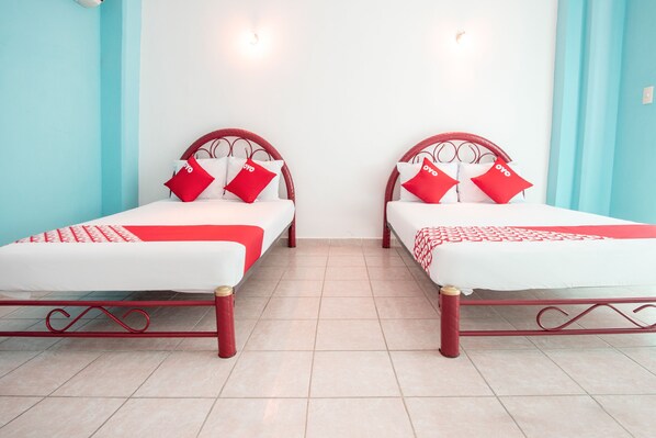 Two twin beds with red and white bedding, a red metal frame, and a tiled floor.