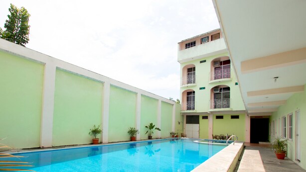 Una piscina con plantas en macetas y un edificio con balcones.