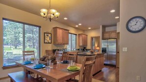 A spacious kitchen with wooden cabinets, a central island, and a dining area with a wooden table and chairs. - AC, Game Room, Family, outdoor seating area, Perks (Sunriver)