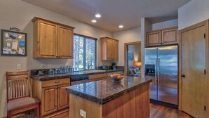 A kitchen with wooden cabinets, a stainless steel refrigerator, and a granite countertop. - AC, Game Room, Family, outdoor seating area, Perks (Sunriver)