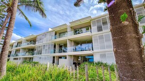 A multi-story hotel with balconies, palm trees, and a clear sky. - Unit 101 Plantation Resort - Rainbow Beach. Plantation Resort. Second Floor. Aircon. Pool. Spa.Wifi (Rainbow Beach)