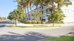 A modern apartment building with balconies, surrounded by palm trees and a well-maintained lawn. - Unit 101 Plantation Resort - Rainbow Beach. Plantation Resort. Second Floor. Aircon. Pool. Spa.Wifi (Rainbow Beach)