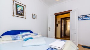 Un dormitorio con cama, almohadas, una colcha y un cuadro en la pared.