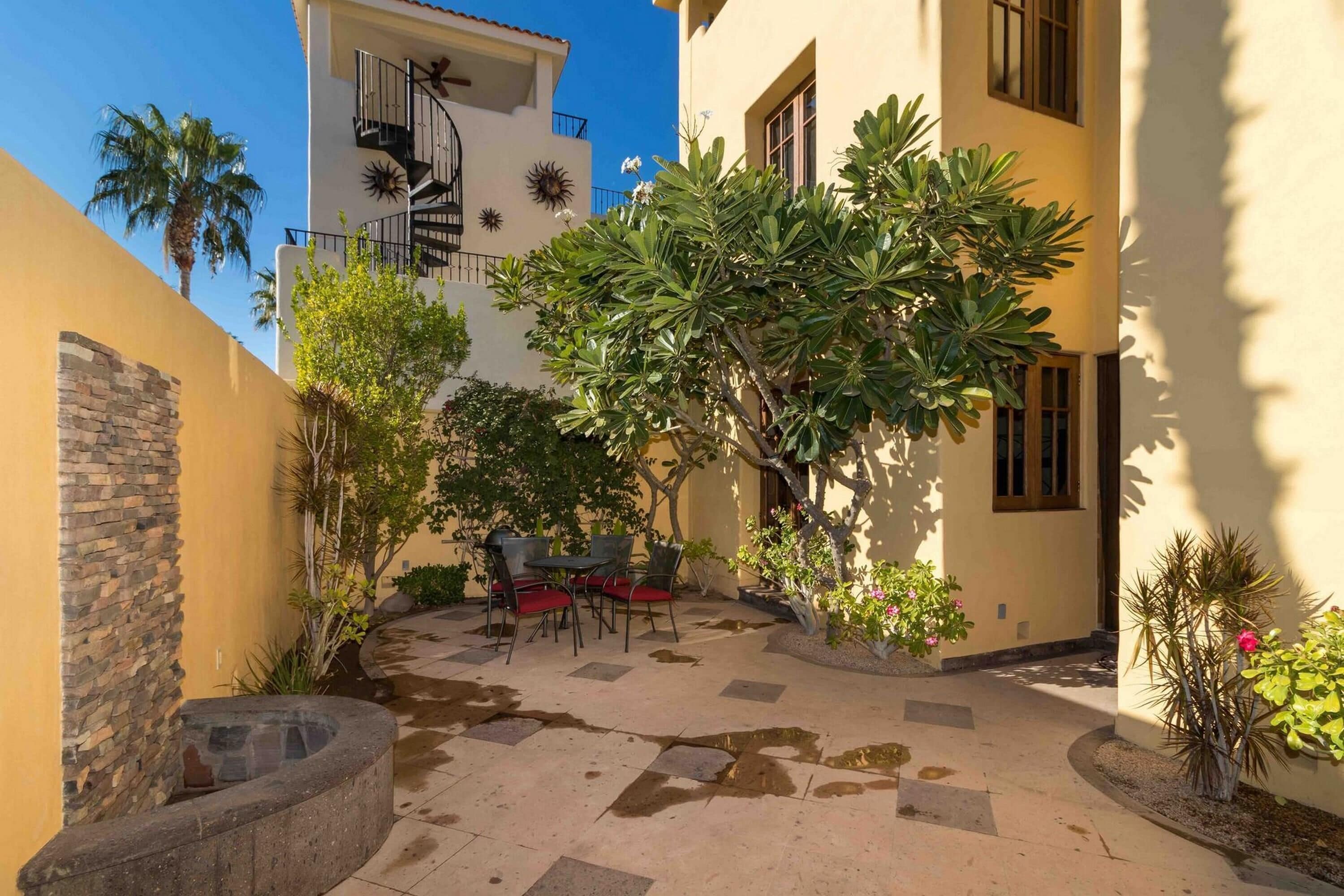 A courtyard with a stone fire pit, outdoor seating, and a variety of plants.
