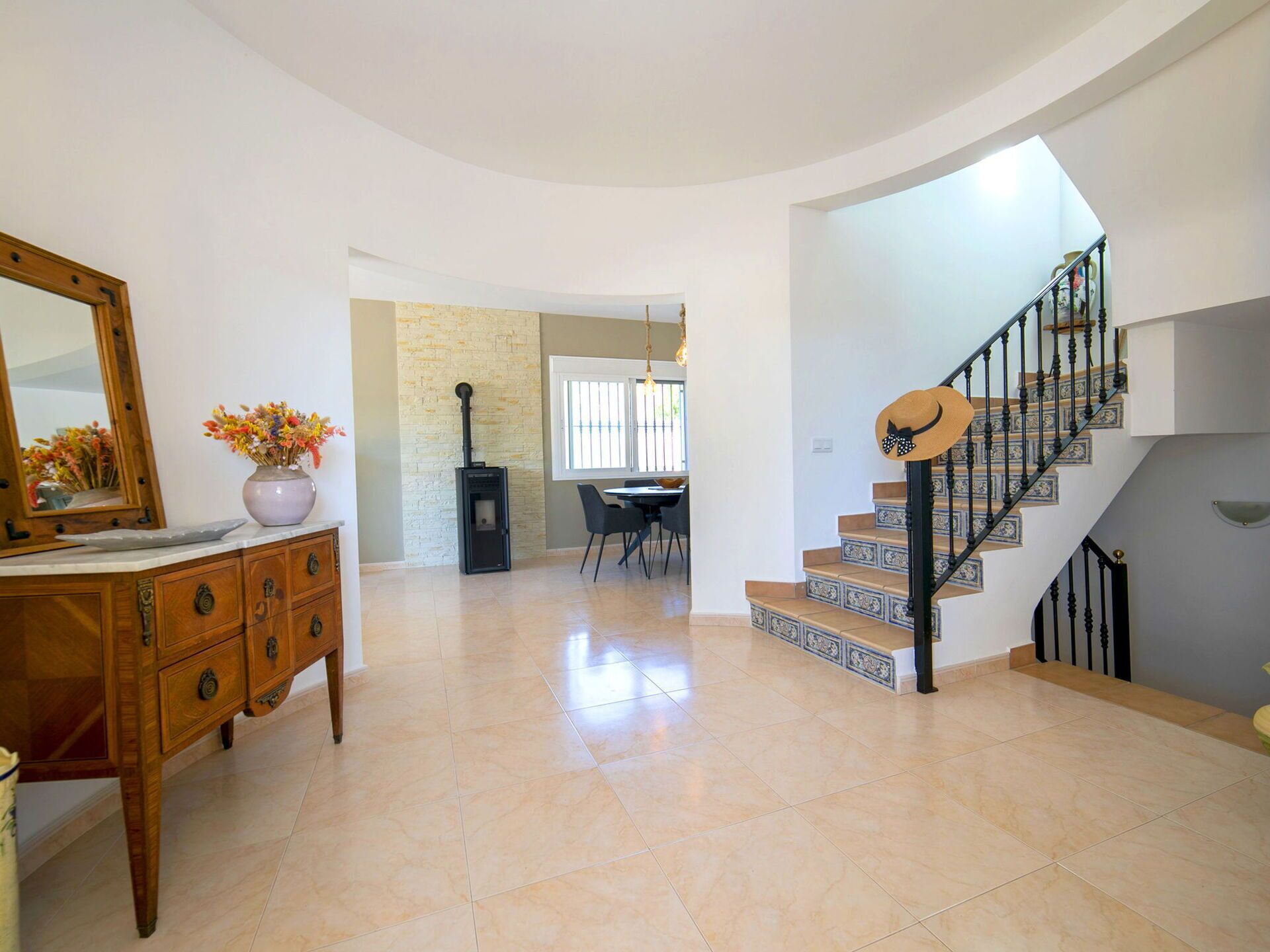Amplia sala de estar con una escalera curva, chimenea y comedor.