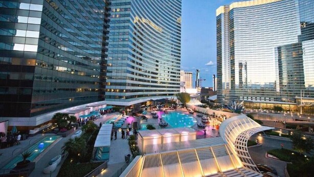 A modern hotel with a rooftop pool area, surrounded by high-rise buildings. - City Center! | Panoramic Corner Suite at Vdara (Las Vegas)